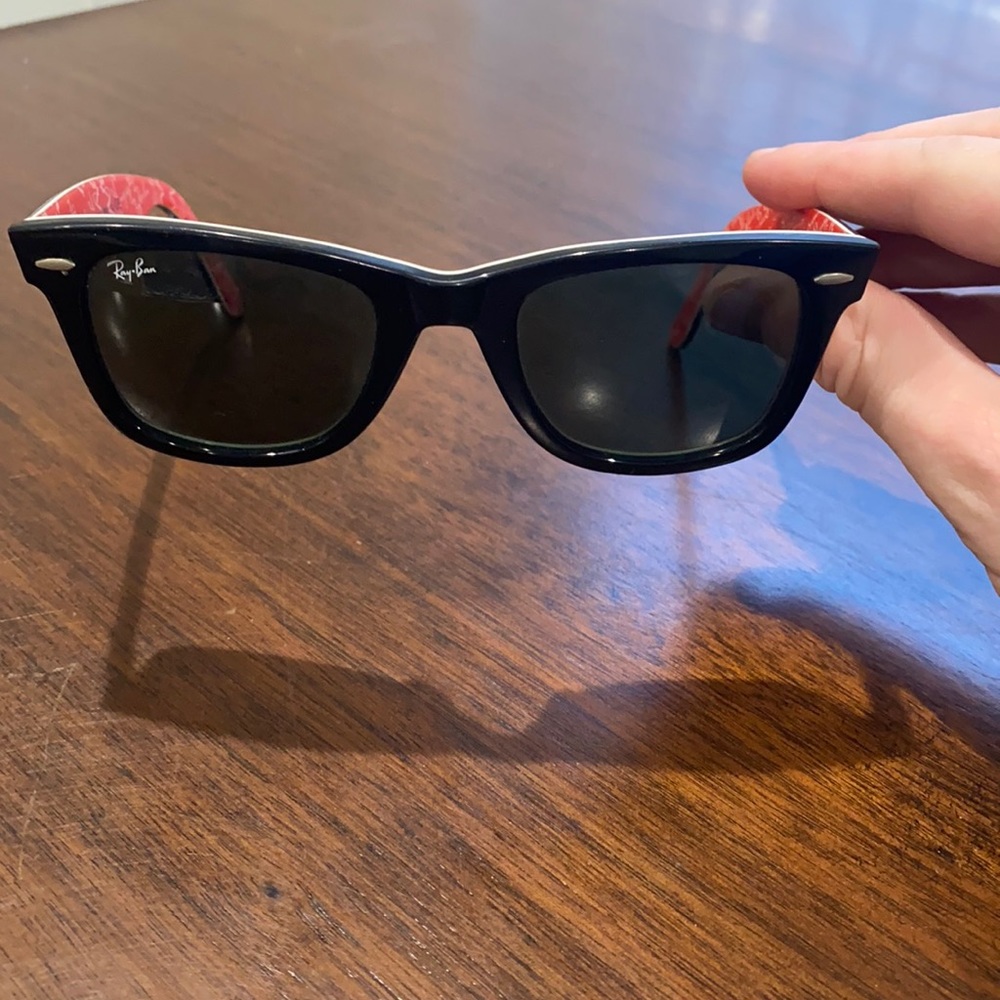 Black ray ban wayfarer sunglasses with red ray ban inscribed inside.